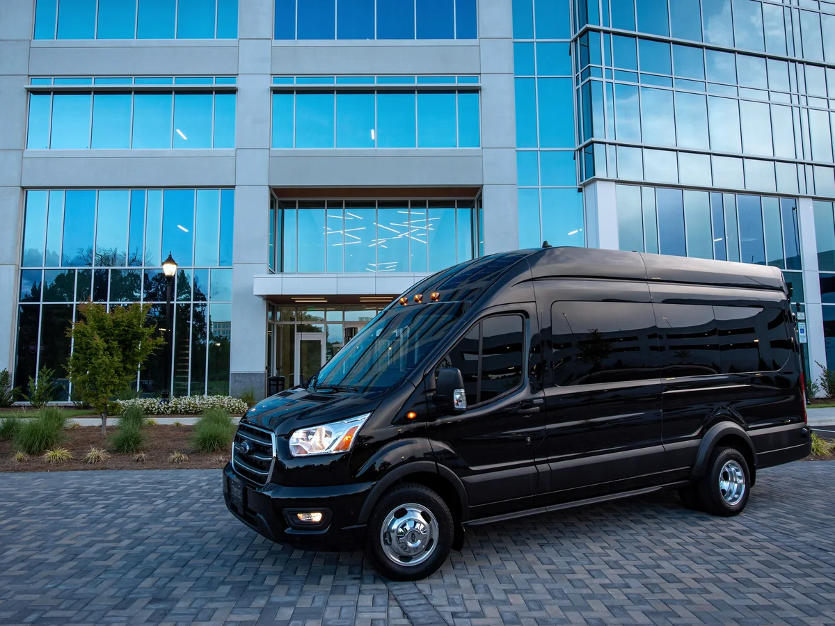 Minibus sombre stationné devant un immeuble de bureaux vitré